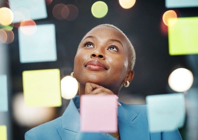 WTW colleague mapping ideas on a glass wall of sticky notes